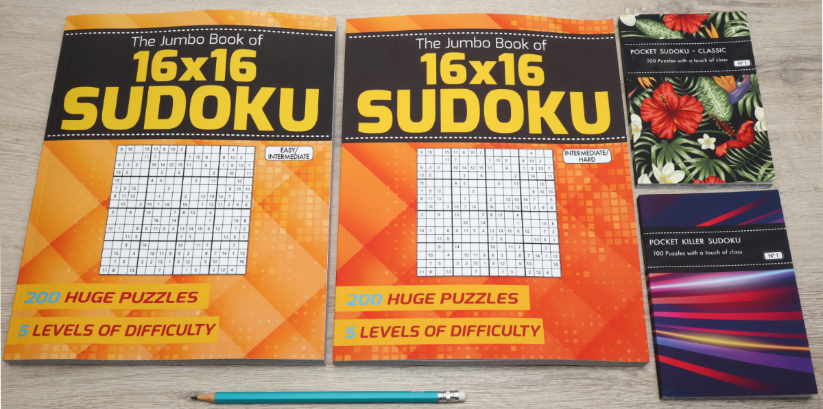 Two volumes of the jumbo book of 16x16 sudoku next to two pocket sudoku books